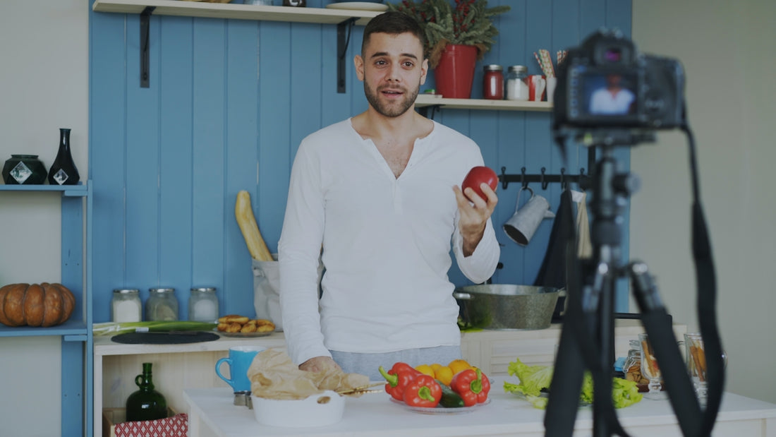 Man holding apple in kitchen recording video