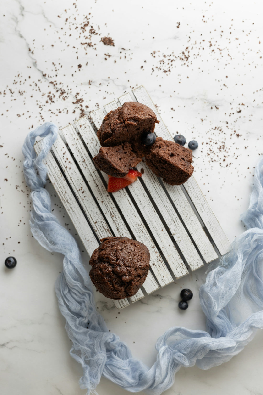 chocolate muffins with strawberries and blueberries on a wooden board