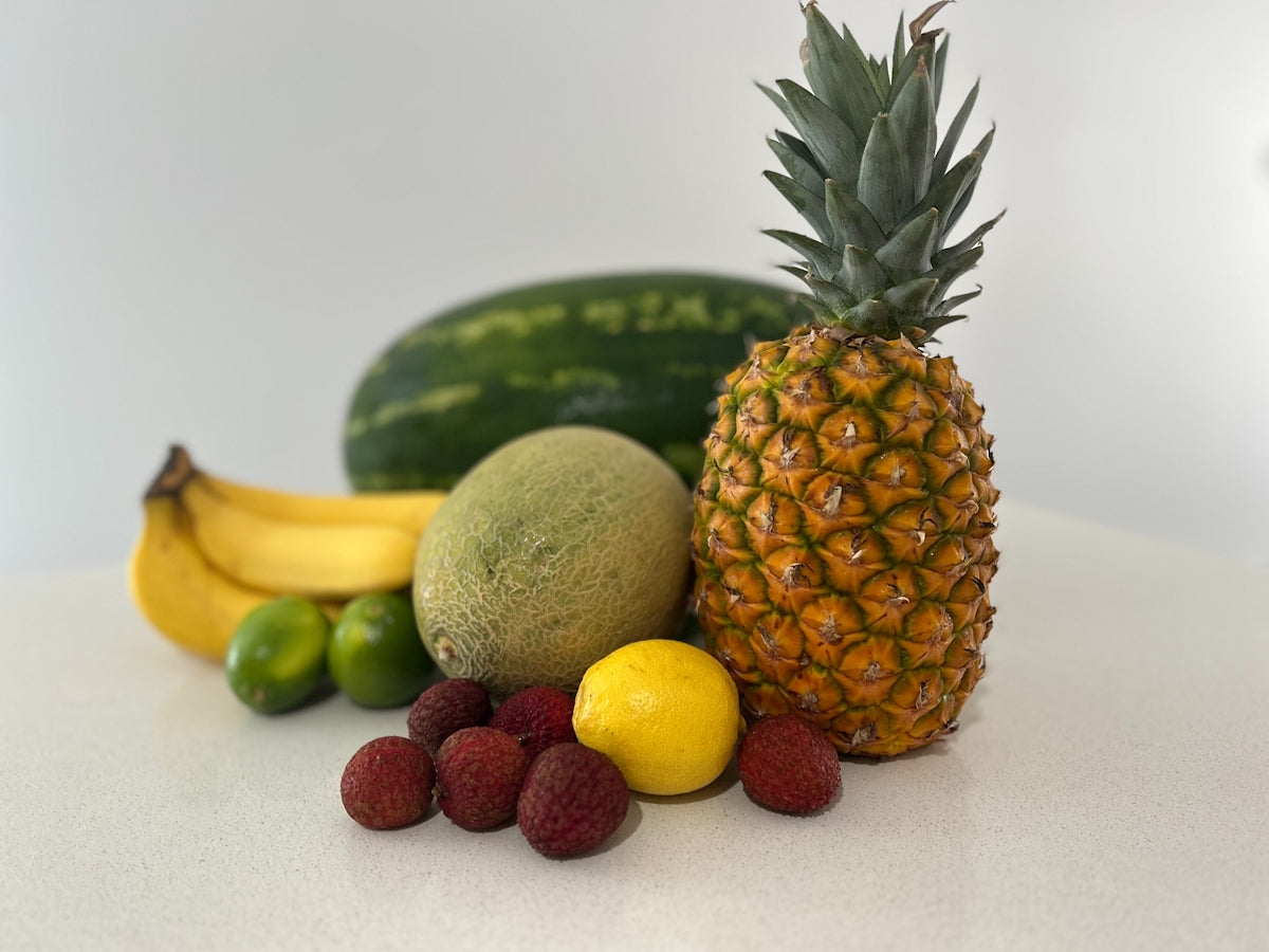A table topped with a pineapple, bananas, and other fruits